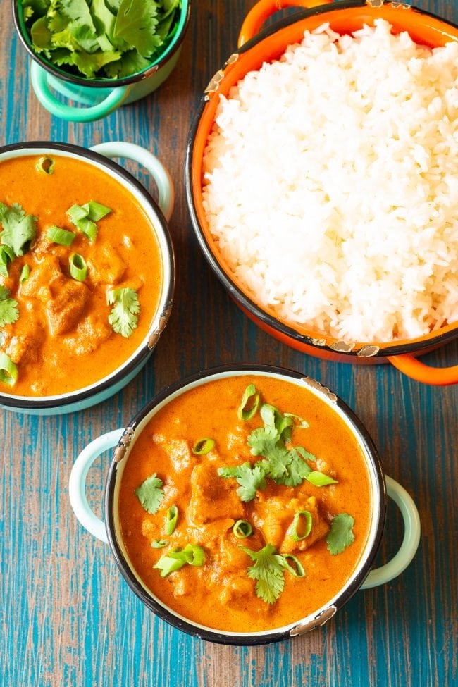 over head shot of instant pot butter chicken in two bowls with a bowl of rice. 